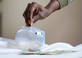 Person Putting Coin in a Piggy Bank